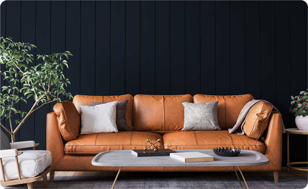 Image of interior decor, a brown leather couch with throw pillows, a coffee table, and green house plant