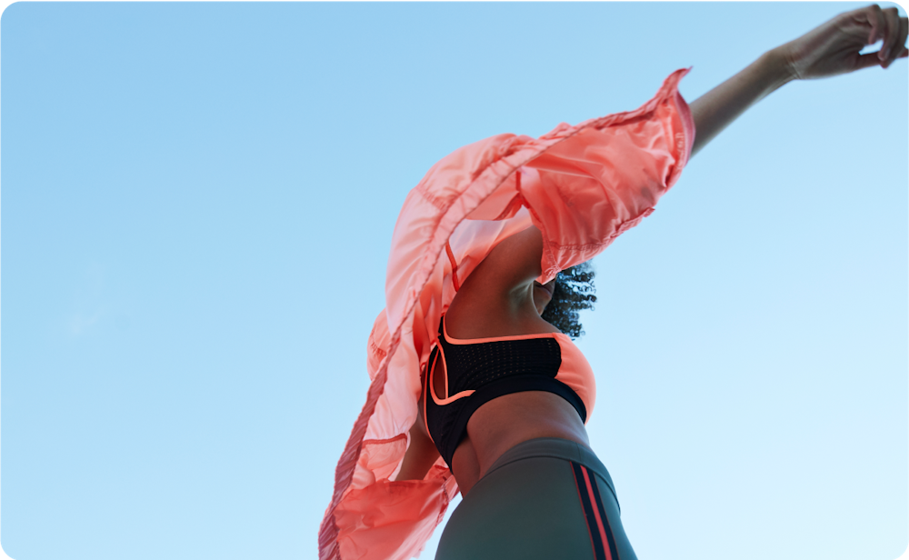 woman in workout gear with arms outstretched to the sky